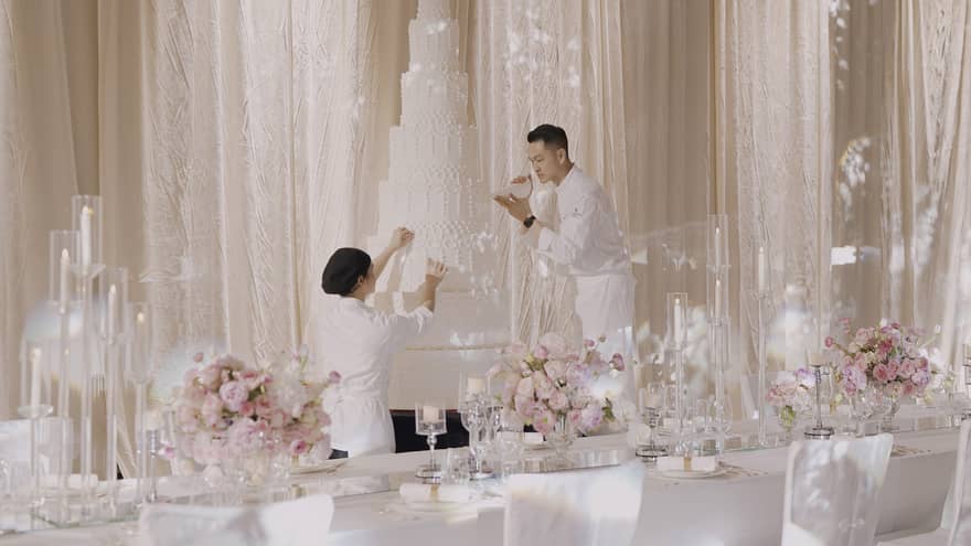 Man and woman put finishing touches on an extra-tall wedding cake