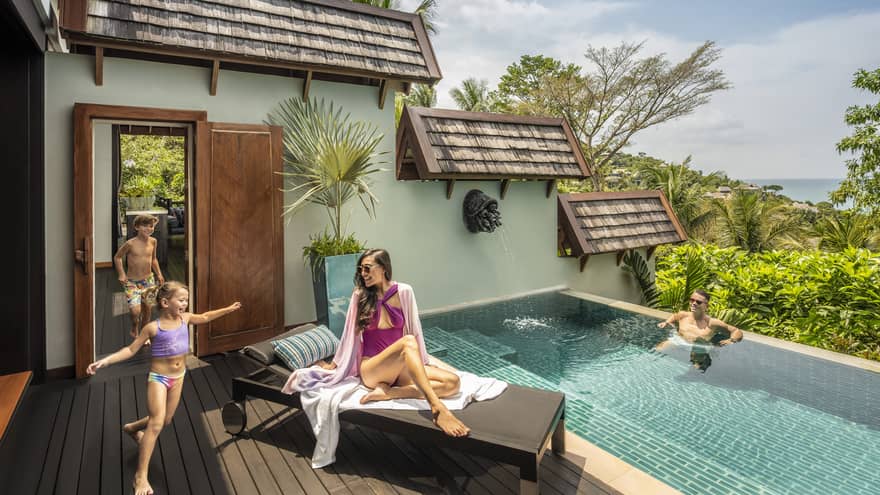 Family of four relaxes poolside outside their villa
