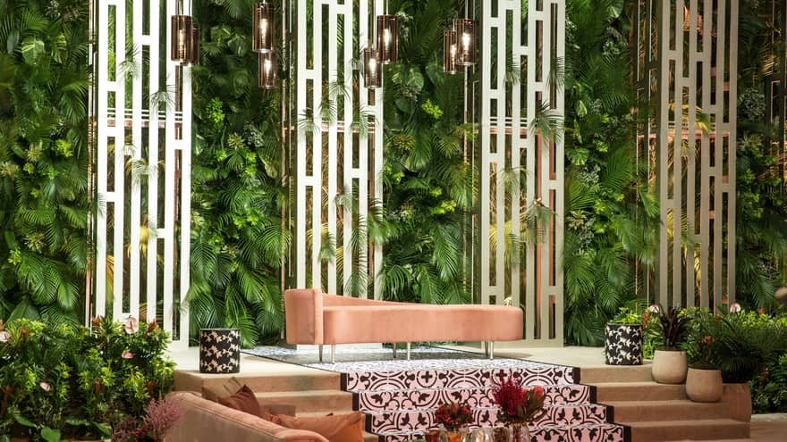 Al Bidaa Ballroom, pink chaise lounge chair on small stage under modern pillars, plant filled wall