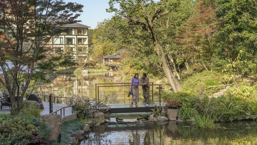 Couple stands on foot bridge overlooking koi pond