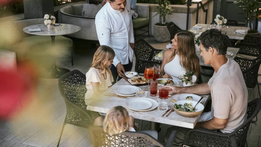 Family of four dines at a table on a restaurant terrace