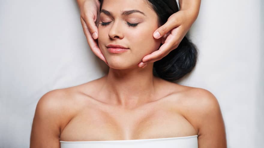 Woman with eyes closed as hands massage her face