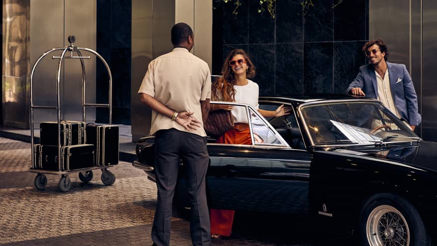 Man welcomes woman getting out of convertible car