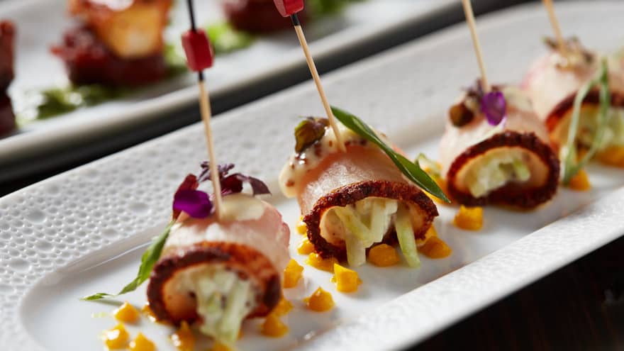 Bacon wrapped hors d'oeuvres with toothpicks on white platters