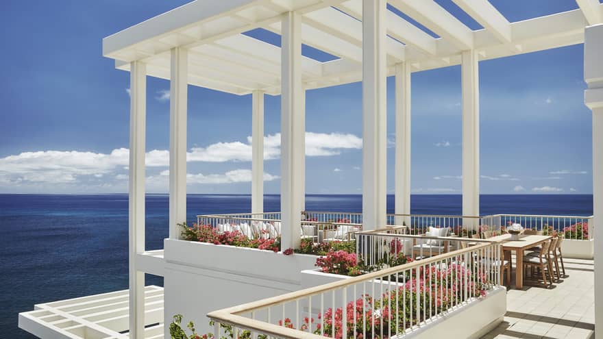 Penthouse Suite patio tables, chairs under white pergola, tropical pink flowers