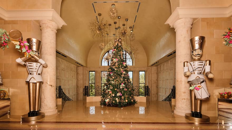 Hotel lobby decorated for the holidays with a large Christmas tree in the centre and two large gold-and-white toy soildier statues
