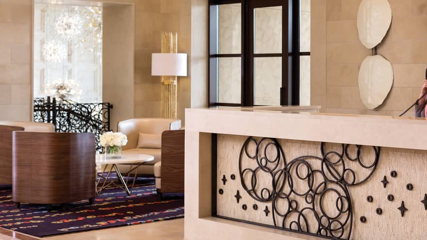 Hotel staff holds telephone behind large marble reception desk in lobby