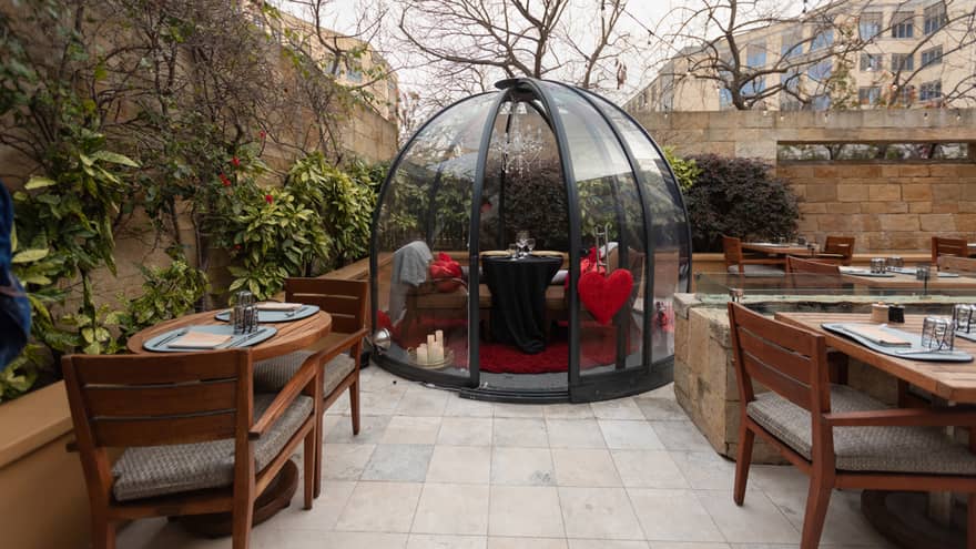 An outdoor terrace with a dining set up under a dome