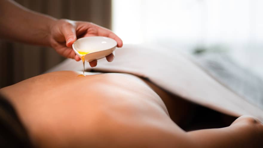 A spa staff member pouring liquid onto a woman?s back.