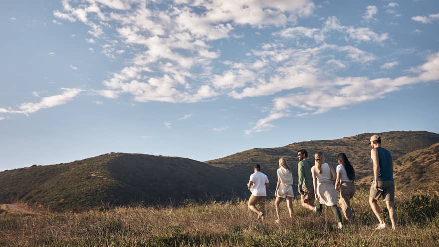 A group of people hiking along a mountain on a sunny day.