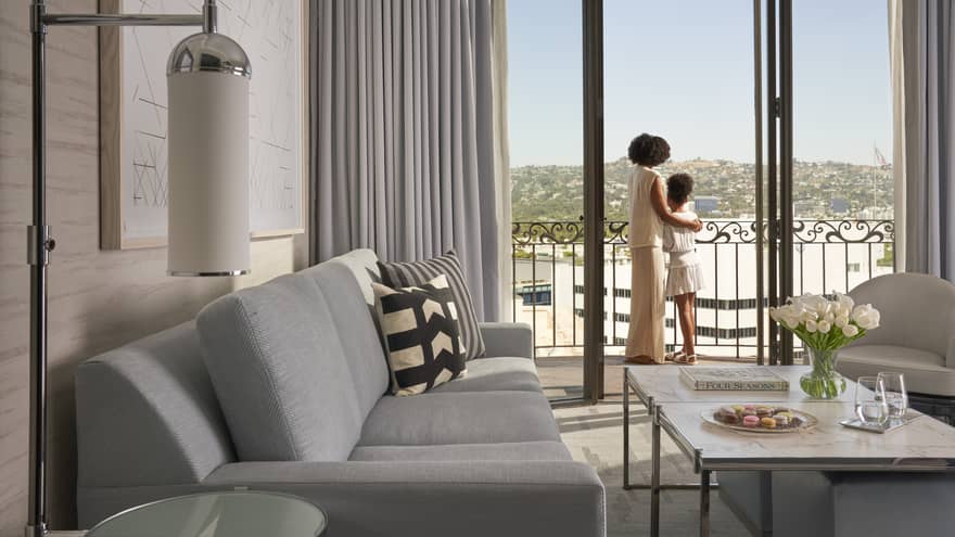 A mother and daughter looking out of a hotel window.