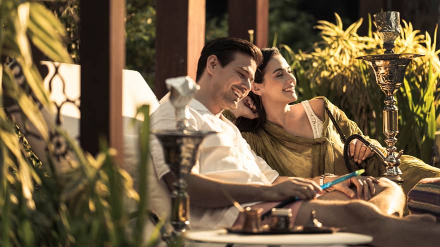 A couple sits together on lounge chairs outside at Four Seasons Hotel Kuala Lumpur