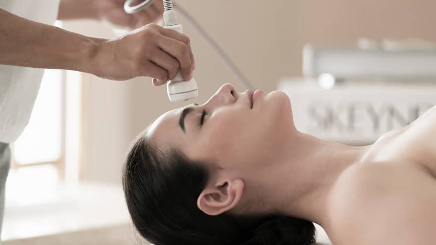 Spa attendant applies a facial to a guest