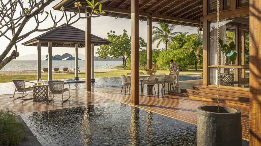 Private pool terrace and wooden deck under pergola, looking out to green lawn and Langkawi beach