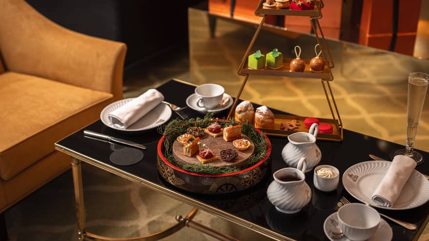 Festive afternoon tea setup on black glass coffee table