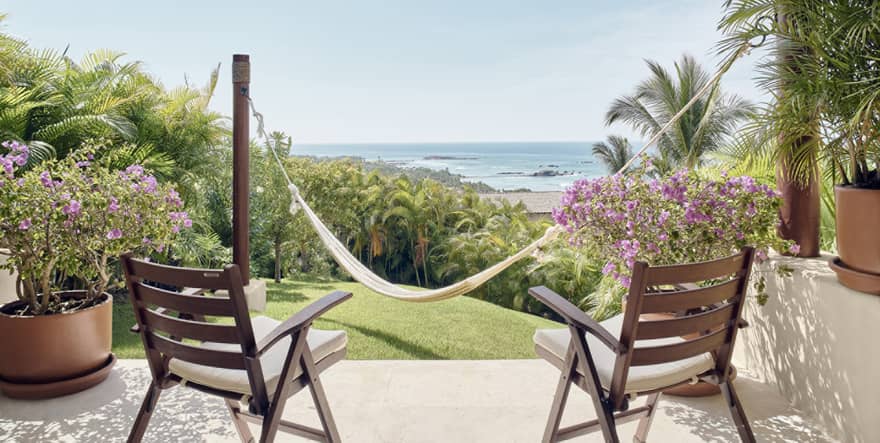 Private terrace with two wooden chairs, hammock on small grass yard, ocean view