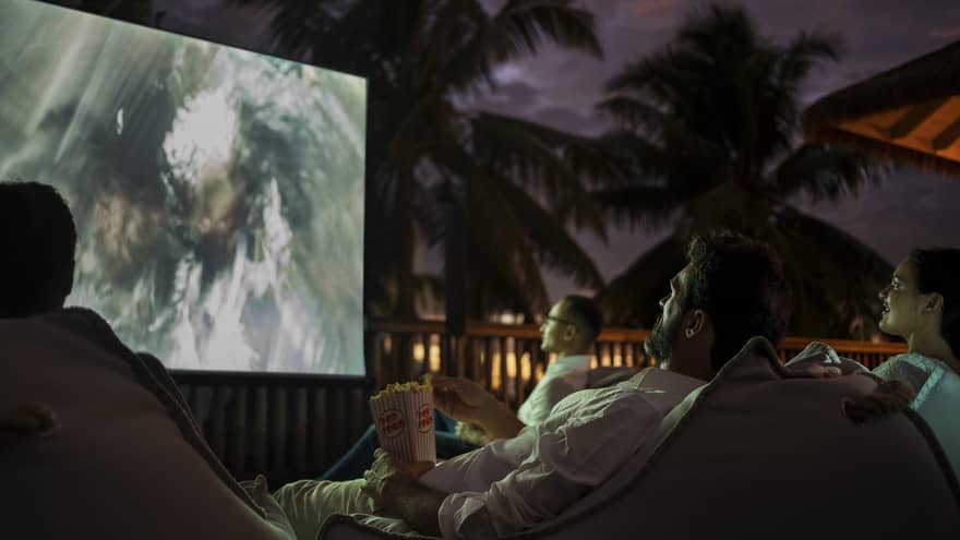 Group of people sit on bean bags with popcorn watching movie under the stars 