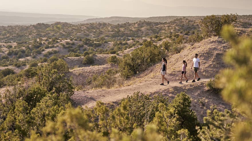 A family of three hiking over sand.