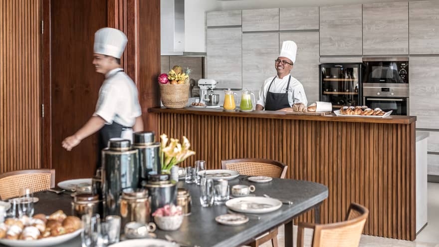 Smiling chefs prepare breakfast at Imperial Villa kitchen private bar, near set table with black vases