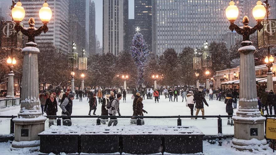 Ice skaters navigate a large rink with the city as a backdrop