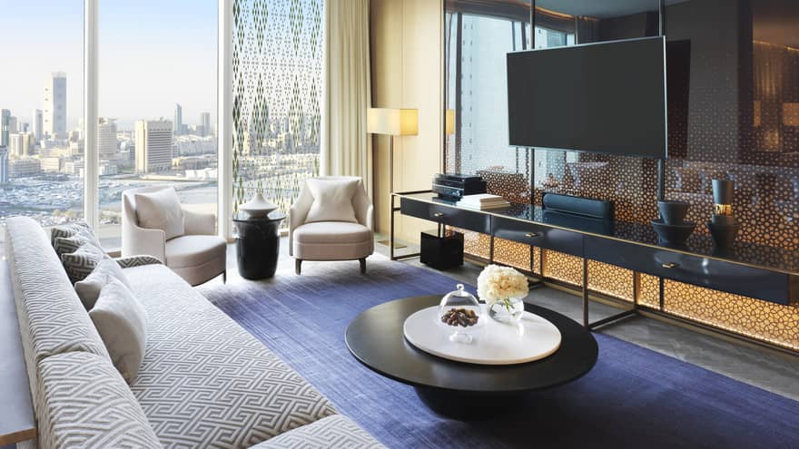 State Suite long white sofa, two modern armchairs by sunny window, large TV above long table