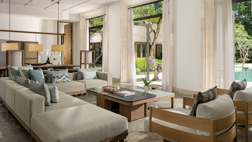 Indoor living room with large sectional sofa and two chairs, three doors opening to private pool terrace, in a private residence at Four Seasons Resort Bali at Jimbaran Bay