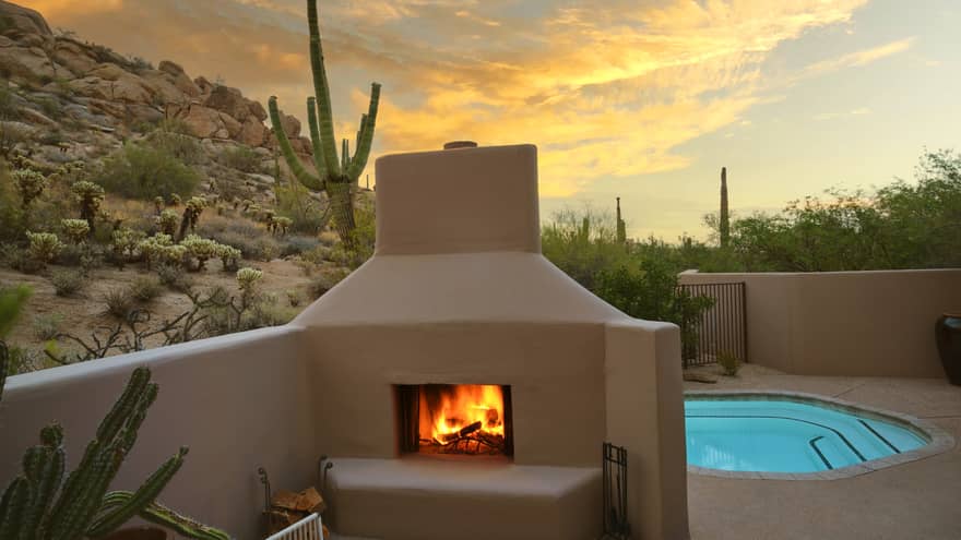 A pool beside a fire pit with a chair, surrounded by desert views