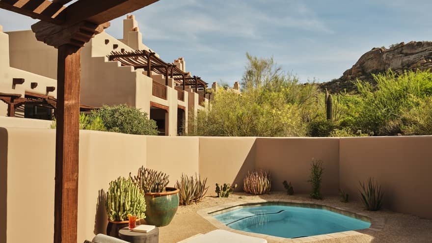 Plunge pool and two sun loungers on a walled-in terrace surrounded by desert landscape