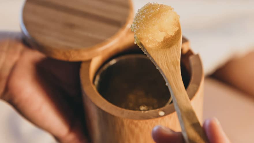 A spa staff member scoops some sugar scrub out of a bamboo container in Hawaii