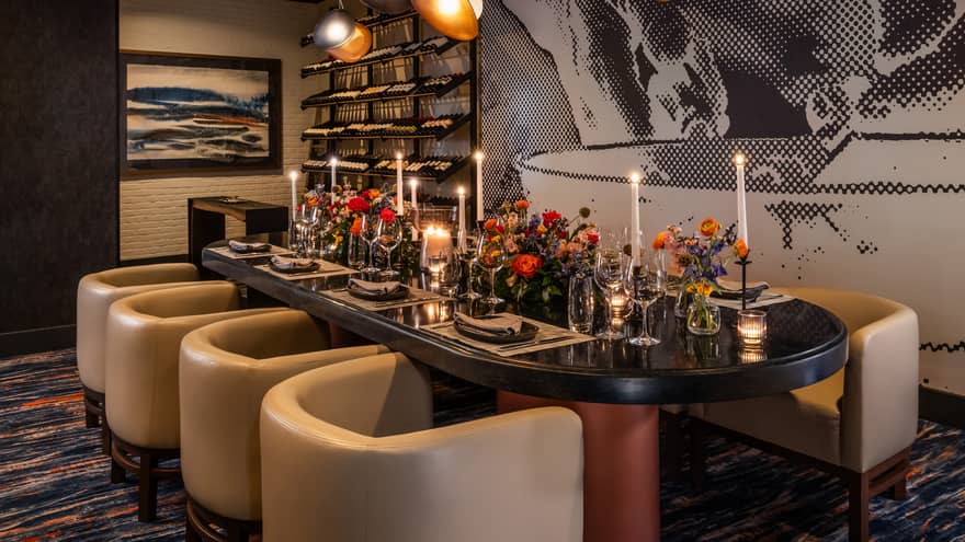 Dining table set with flower vases and candles with lights above and wall art