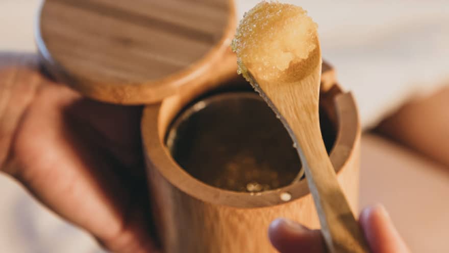 A spa staff member scoops some sugar scrub out of a bamboo container in Hawaii