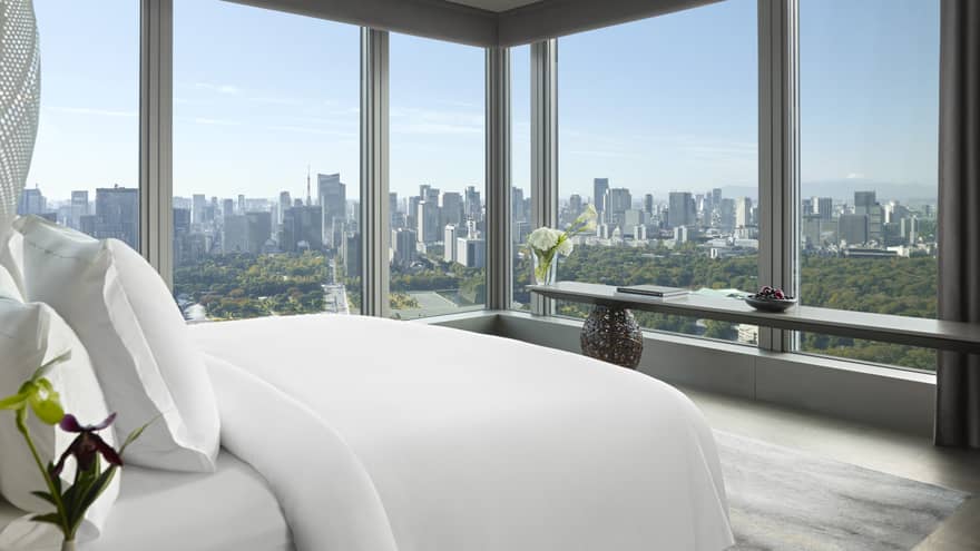 Panoramic hotel room with a king bed, side table with flowers and long console table with orchids