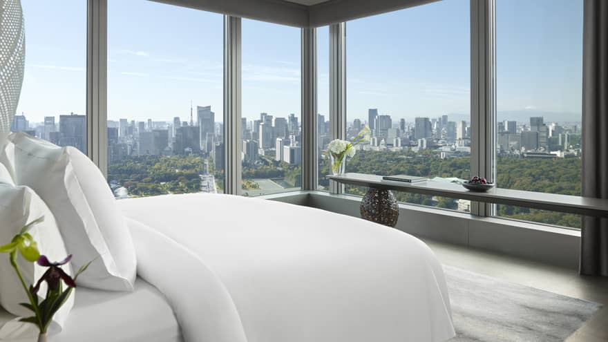 Panoramic hotel room with a king bed, side table with flowers and long console table with orchids