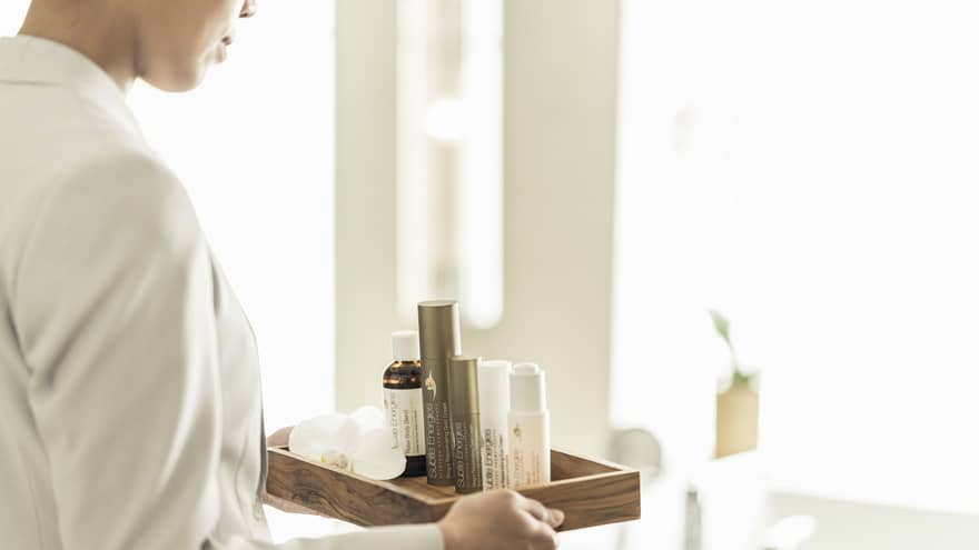hotel staff carrying tray of spa products