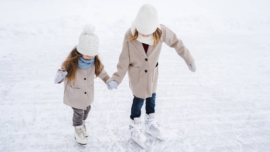 Two young girls ice skating.