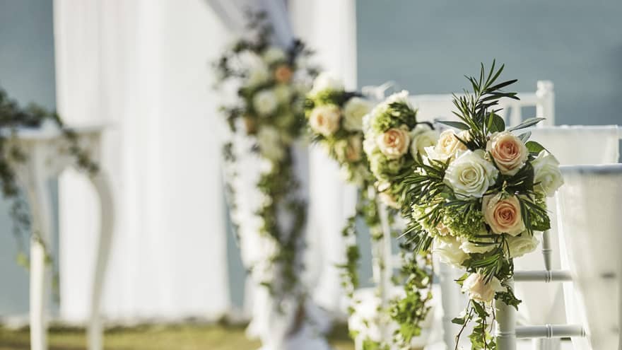Pink and white rose bouquets on wedding chairs, table