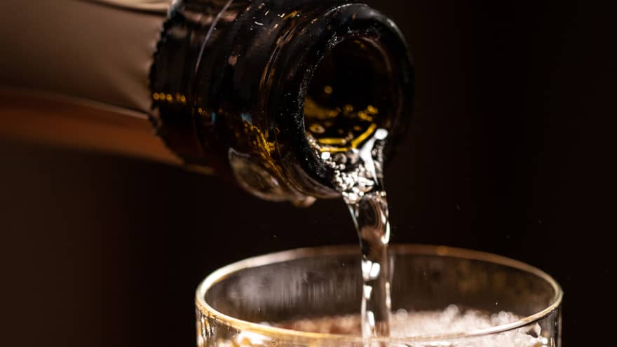 A bottle of wine being poured into a glass.