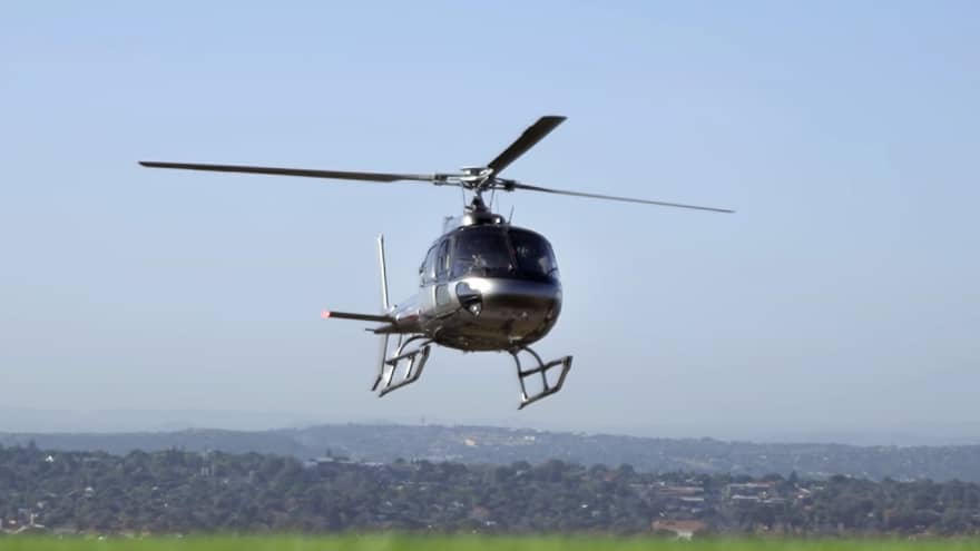 Helicopter hovering over field against blue sky