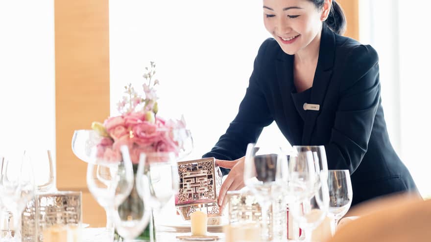Hotel staff sets candle holder on dining table
