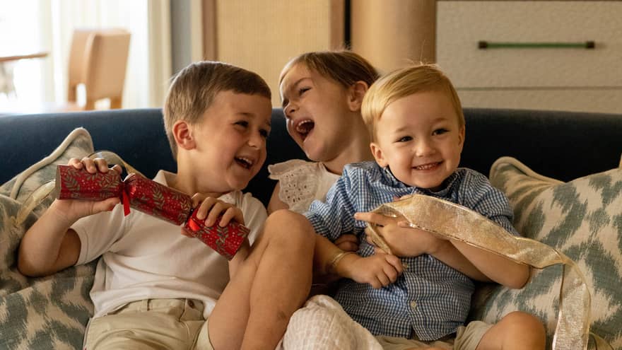 Three young children playing on a sofa.