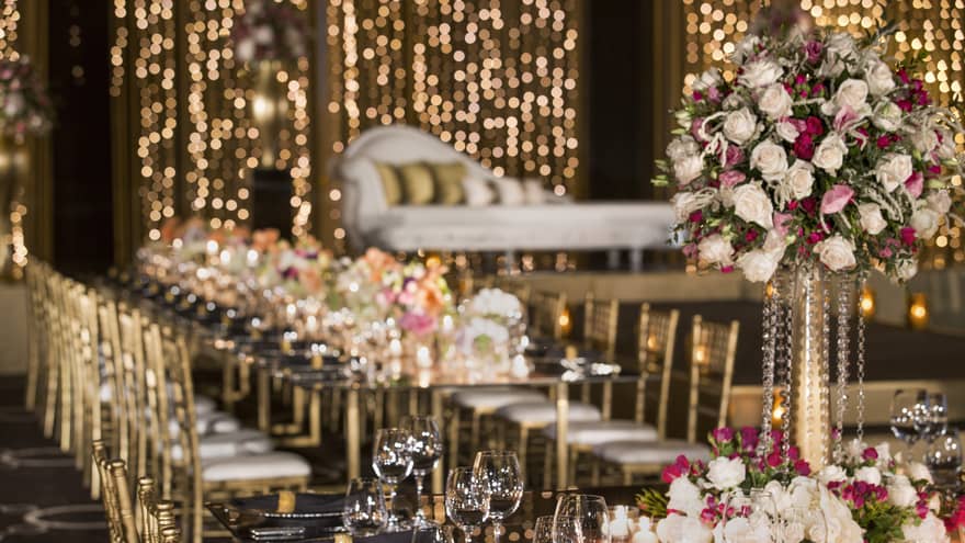 Wine glasses, roses on wedding banquet table before elegant chaise lounge chair 
