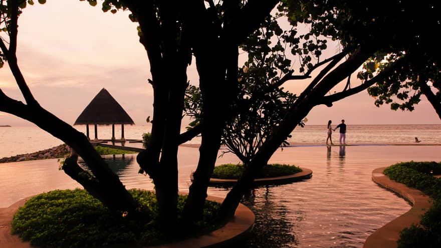 Serenity Pool winding around trees at sunset, silhouette of couple in background