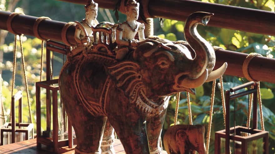 Elephant statues on wood table beside bamboo railing