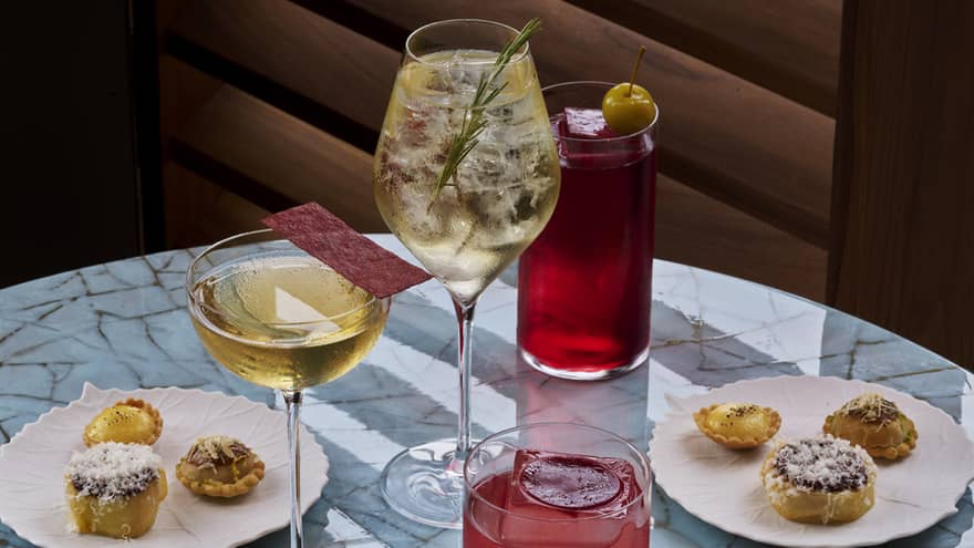 A selection of cocktails on a table with two plates of pastries