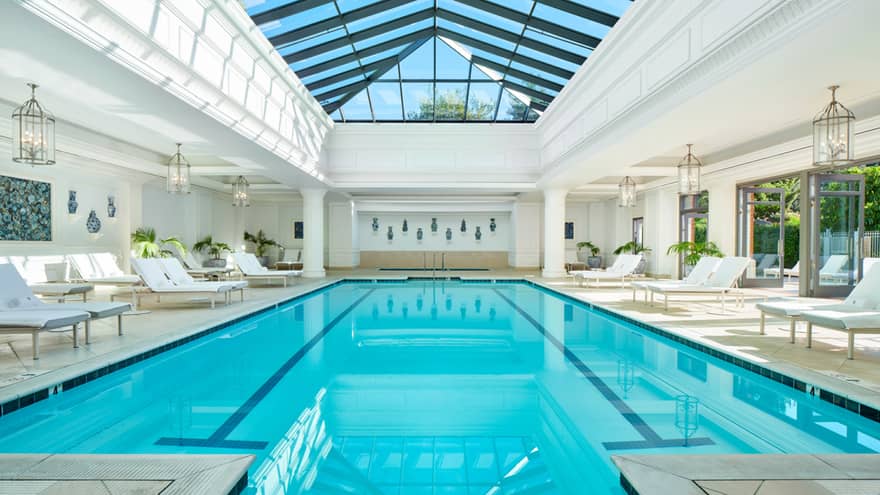 Indoor pool with lounge chairs and ceiling with windows.