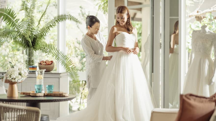 Wedding tailor helps bride in her wedding dress