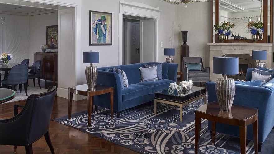 Living room with two blue velvet sofas, blue rug, crown molding and entryway into elegant dining room