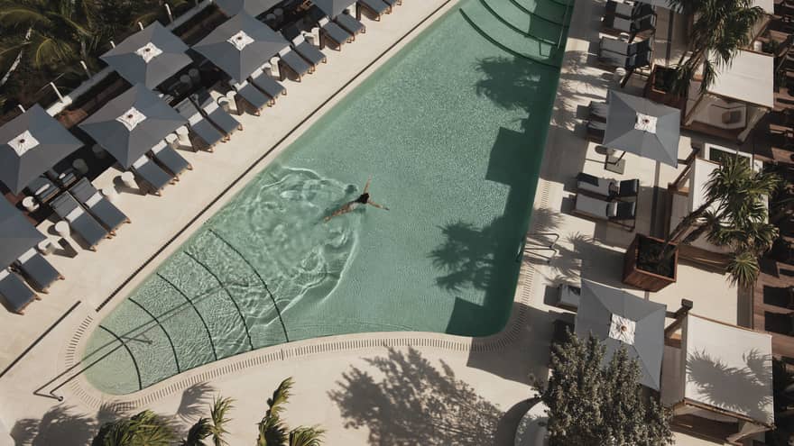 Aerial view of an outdoor pool surrounded by grey lounge chairs and umbrellas, creating a relaxing atmosphere.