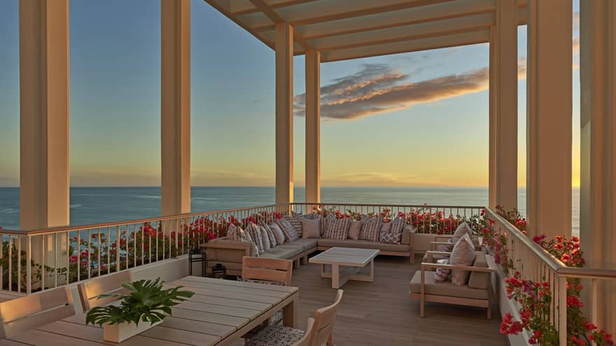 Large lanai overlooking the ocean with lounge furniture and pergola