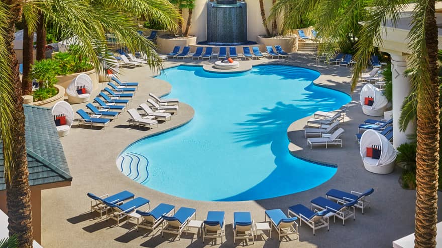 Waterfall in front of blue lounge chairs, curved outdoor swimming pool